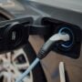 grey sedan hooked to ev charging station