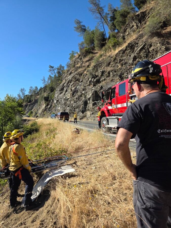 Firefighters from Junction City Volunteer Fire Department, CAL FIRE, and the Weaverville Fire Department prepare for a high-angle rope rescue from the steep embankment above the river.